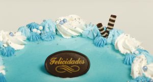 Tarta latina decorada con nata blanca y detalles azules, relleno personalizable.