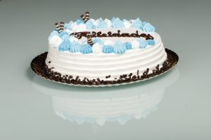 Tarta latina decorada con nata blanca y detalles azules, relleno personalizable.
