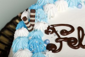Tarta latina decorada con nata blanca y detalles azules, relleno personalizable.