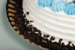 Tarta latina decorada con nata blanca y detalles azules, relleno personalizable.