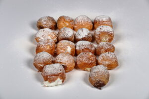 Caja de 18 buñuelos de viento surtidos rellenos de sabores variados, elaborados artesanalmente.