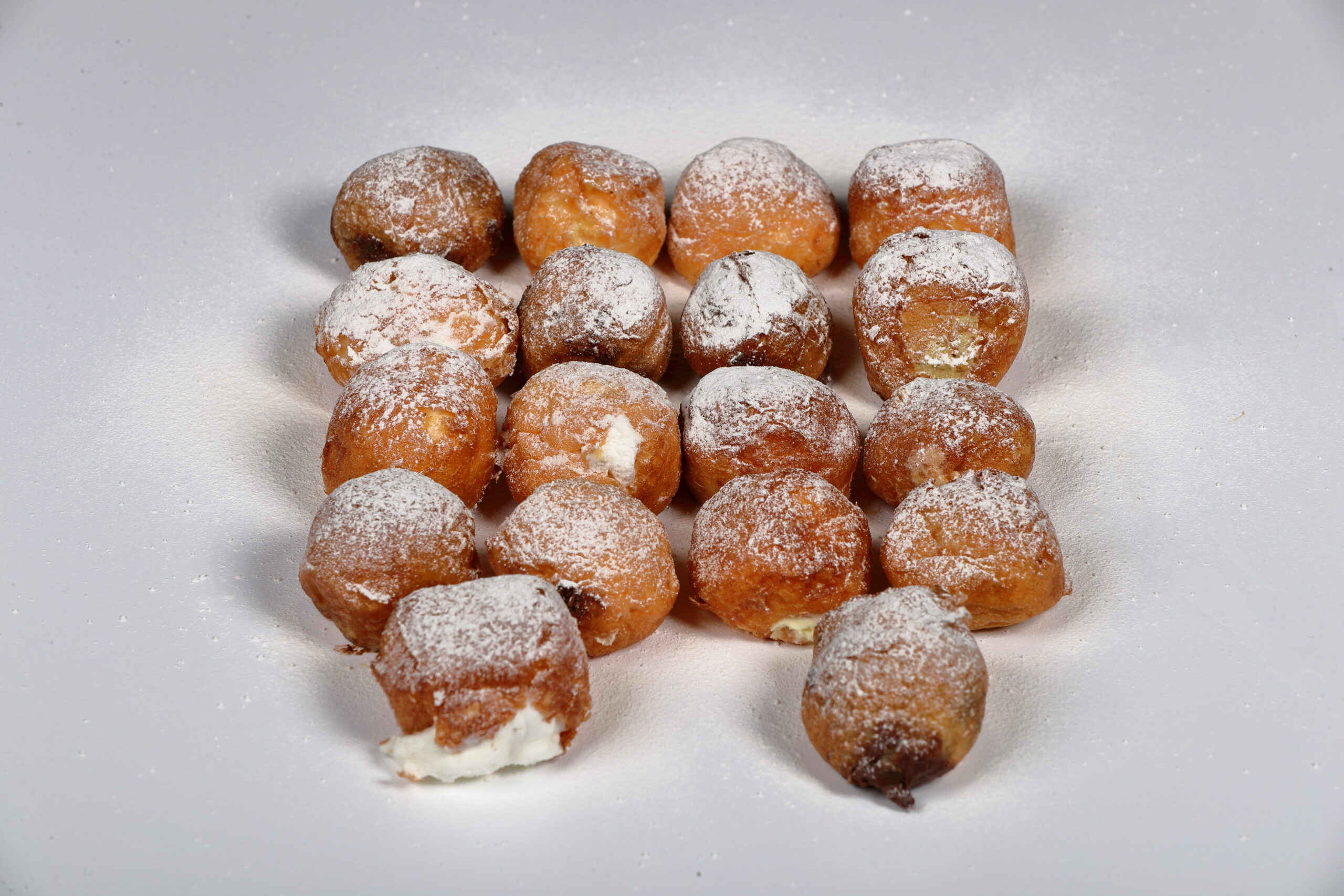 Caja de 18 buñuelos de viento surtidos rellenos de sabores variados, elaborados artesanalmente.