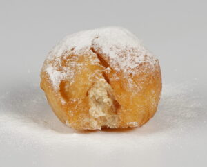 Buñuelo artesanal del Horno Cisneros relleno con crema de galleta Lotus, esponjoso y con sabor a caramelo especiado.